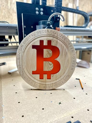 Holzscheibe mit geprägtem Bitcoin-Symbol in roter Farbe.